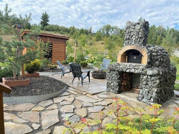 Un patio in pietra con un forno a legna e un'area salotto.