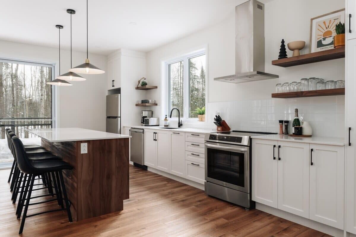 Een moderne keuken met witte kasten, een houten eiland en een groot raam.