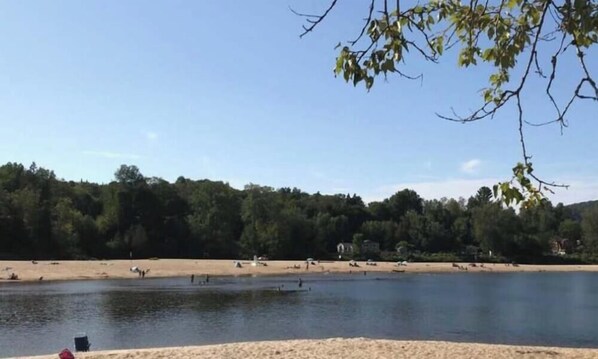 A lakeside view with a sandy beach, trees, and a clear sky. - Peaceful Chalet Tremblant, hot tub lakes & Kayaks (Amherst)