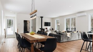 A spacious living area with a wooden dining table, black chairs, and a modern fireplace. - Peaceful Chalet Tremblant, hot tub lakes & Kayaks (Amherst)