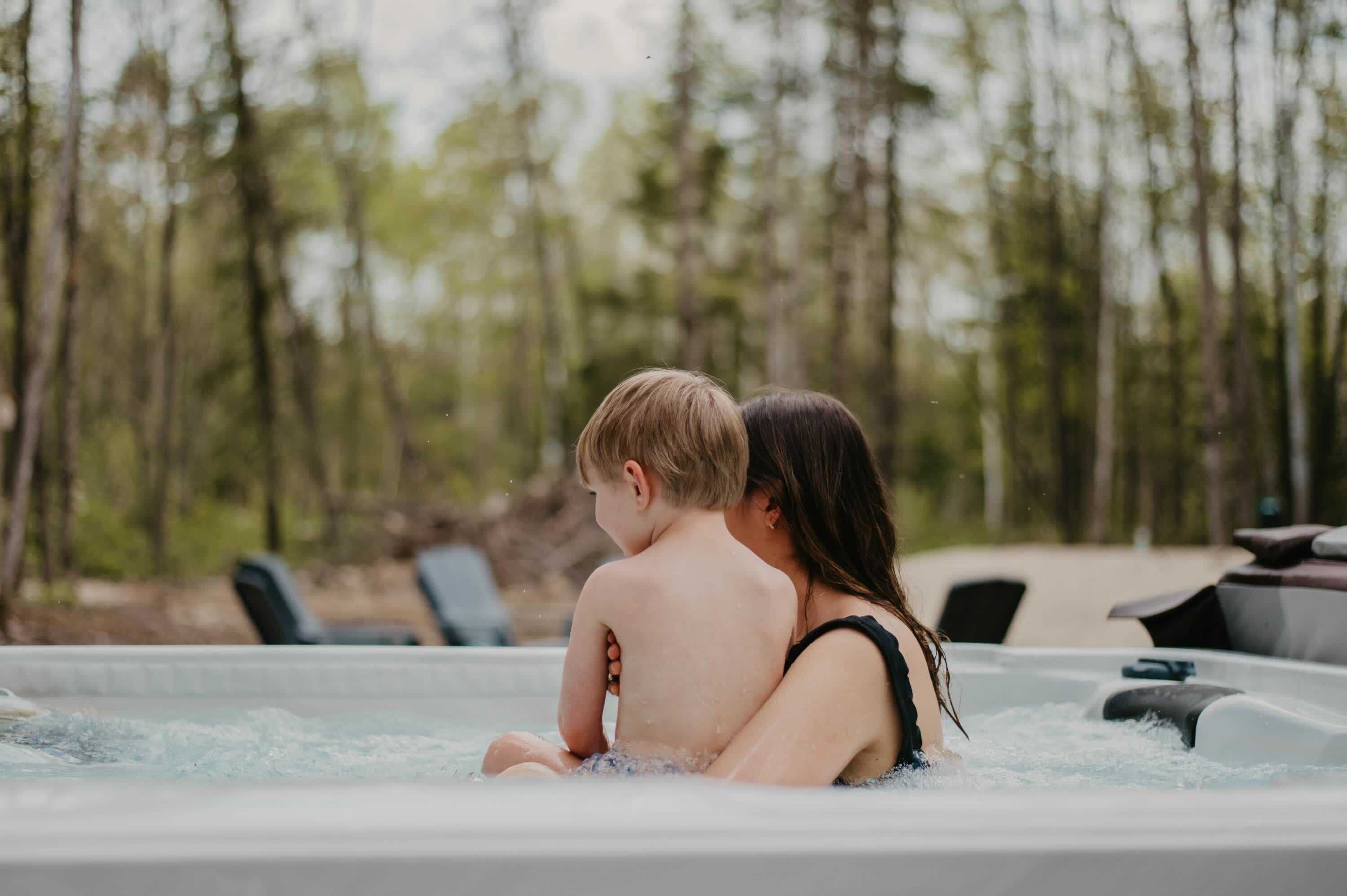 Una pareja en un jacuzzi con un paisaje boscoso al fondo.