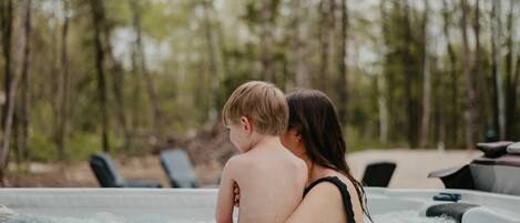 Una pareja en un jacuzzi con un paisaje boscoso al fondo.
