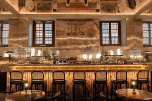 Un bar con mostrador de mármol, varios taburetes y un techo decorativo.