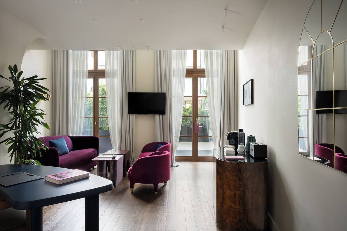 A modern living room with a sofa, armchairs, a coffee table, and a TV.