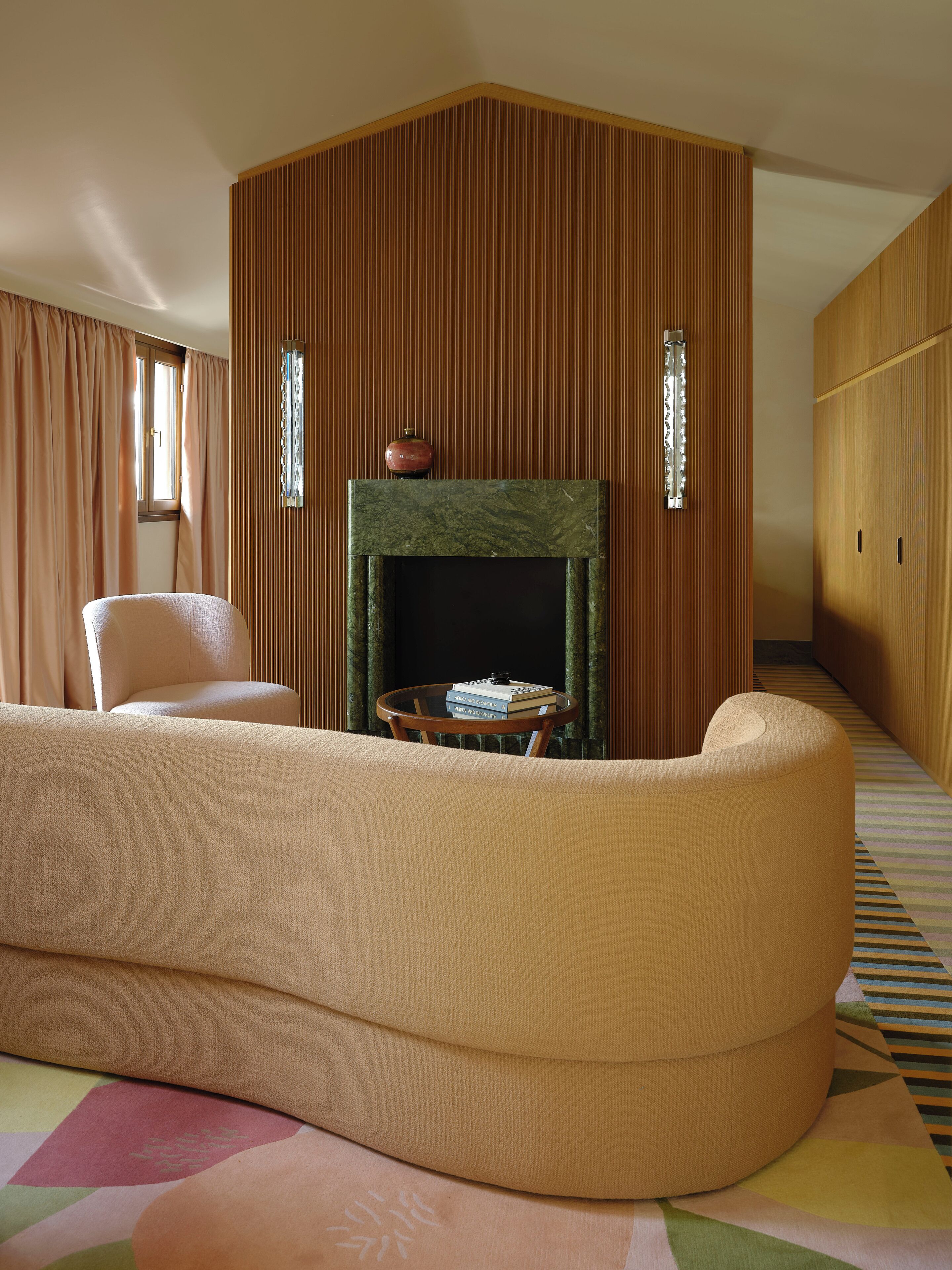 A living room with a sofa, a fireplace, and a window with curtains.