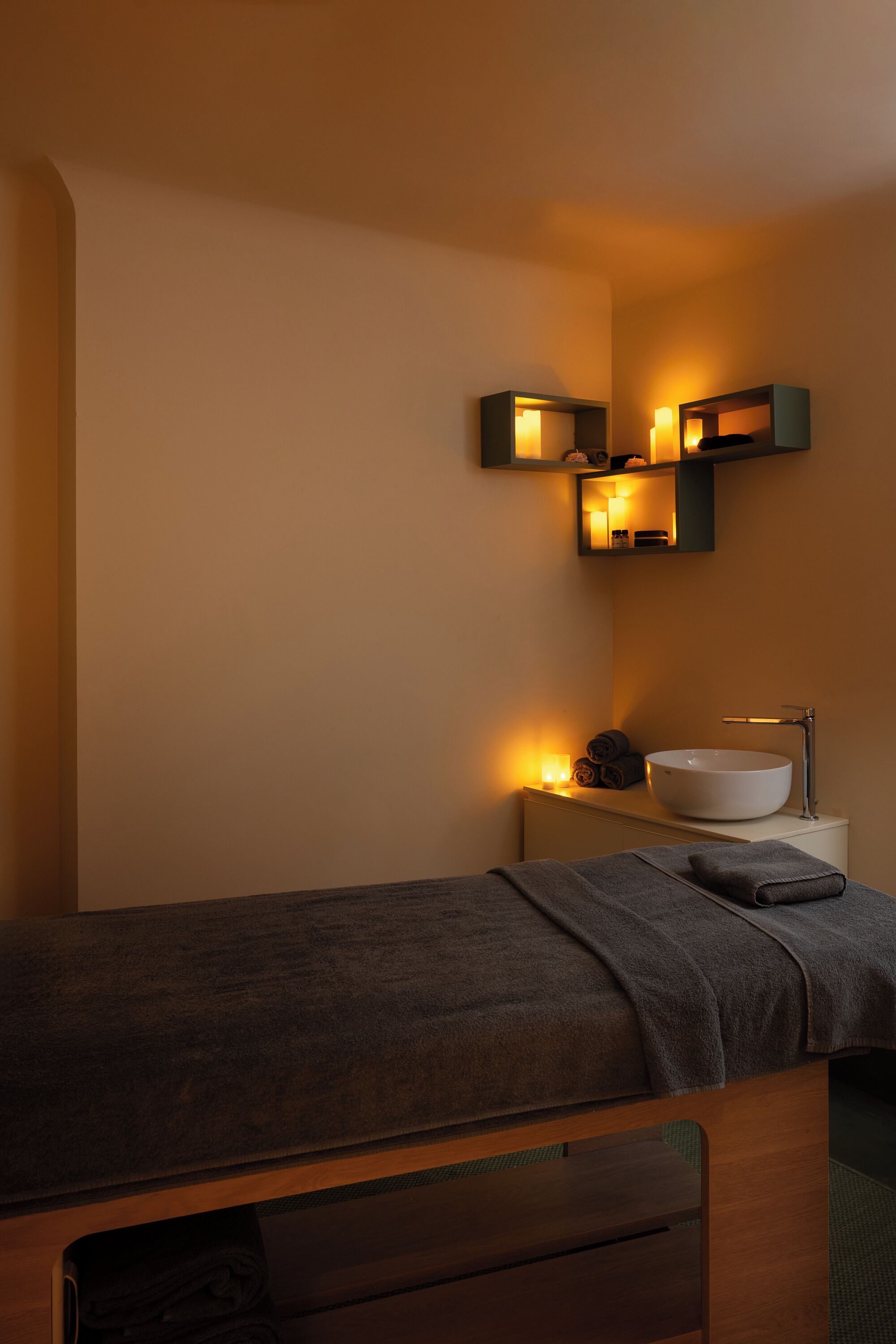 A modern bathroom with a wooden vanity, a large white sink, and wall-mounted lights.