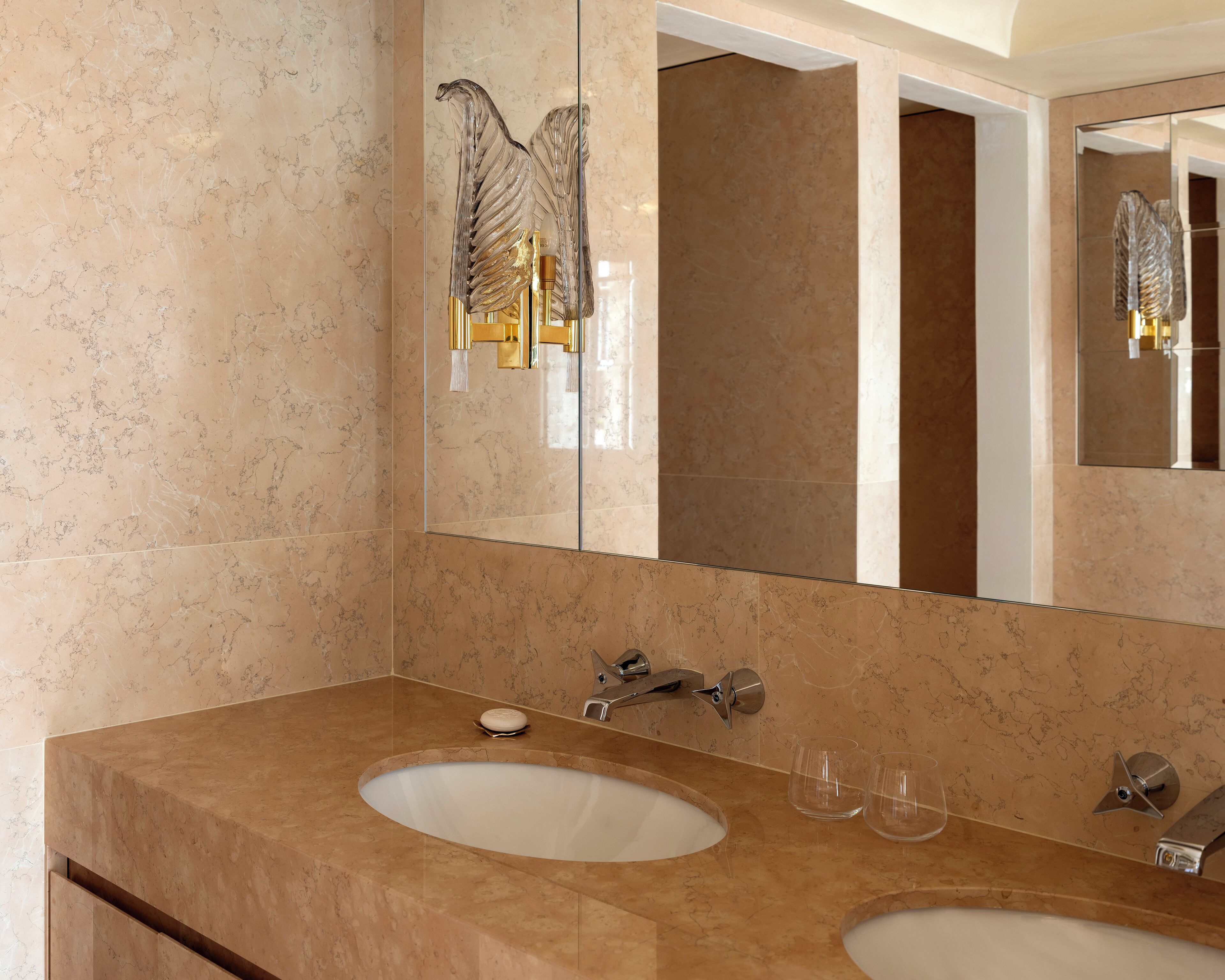 Un baño con dos lavamanos, un espejo grande y una cabina de ducha con paredes de cristal.