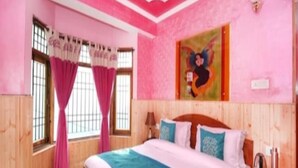 A bedroom with a large bed, wooden walls, pink curtains, and a painting on the wall. - Hotel Mount View Shimla (Shimla)