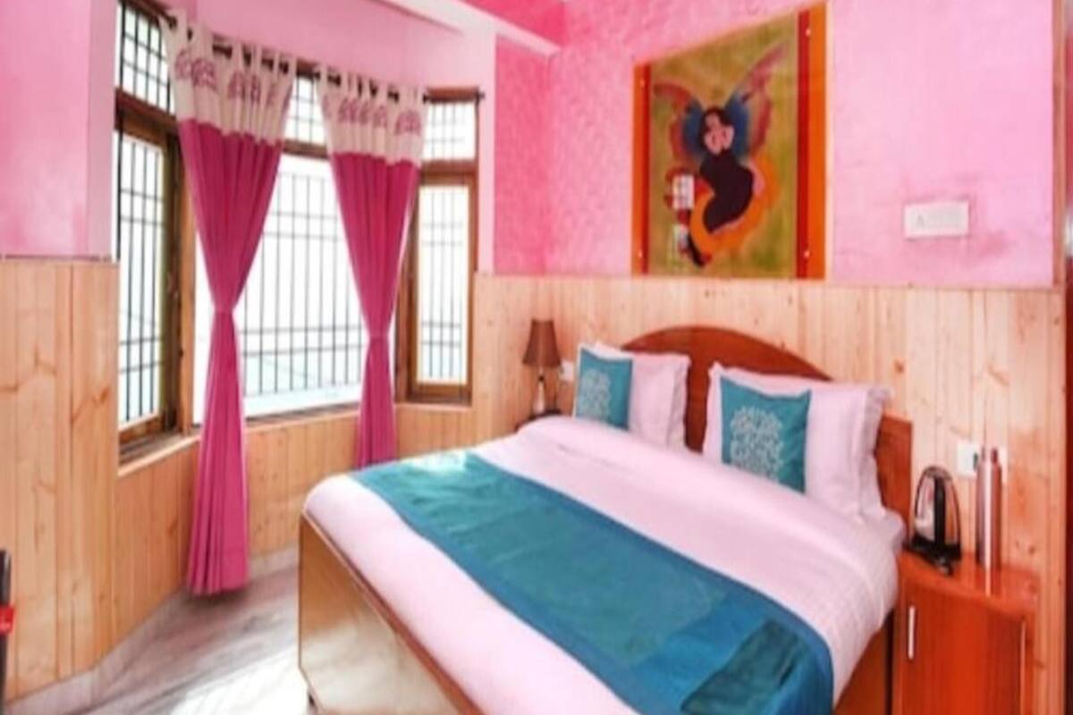 Un dormitorio con una cama grande, paredes de madera, cortinas rosadas y un cuadro en la pared.
