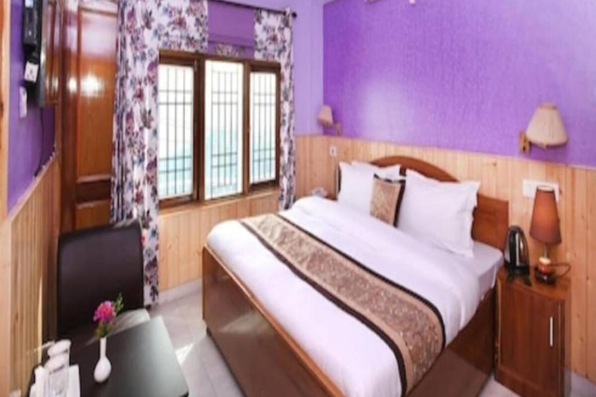 Un dormitorio con cama, escritorio, silla y ventana con cortinas.