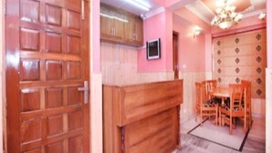 A room with a wooden door, a television mounted on the wall, and a dining area with chairs and a table. - Hotel Mount View Shimla (Shimla)