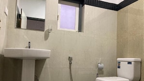Et badeværelse med vask, toilet og bruser.