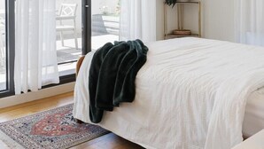 A modern bedroom with a large bed, a potted plant, and a view through a sliding glass door. - StayCentral - The Stanley@Collingwood - Smith St, Collingwood - 2 Bedrooms, 2 Beds, 1 Bathroom1, 1 secure undercover parking spot. (Collingwood)