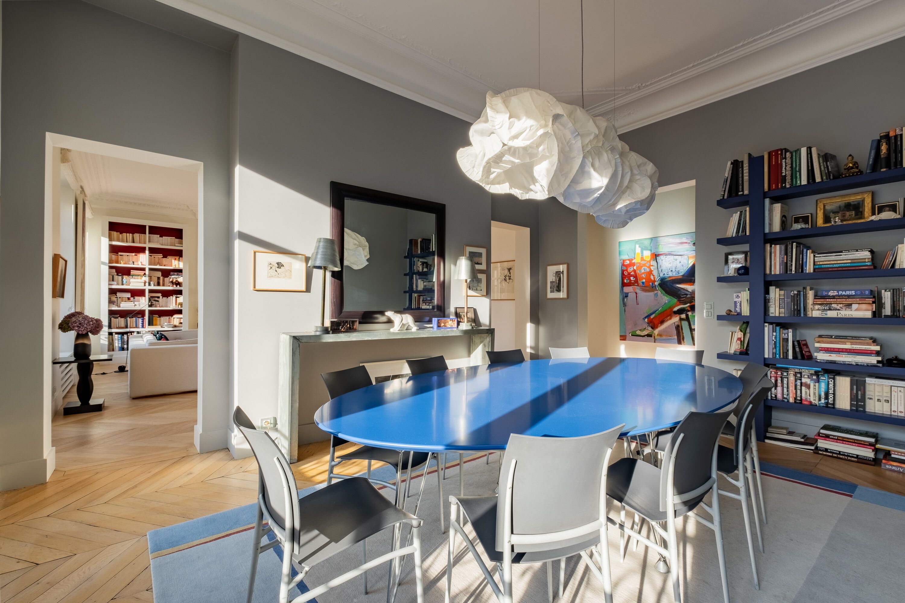 Ein moderner Essraum mit einem blauen Tisch, weißen Stühlen und einer großen weißen Chandelüster.