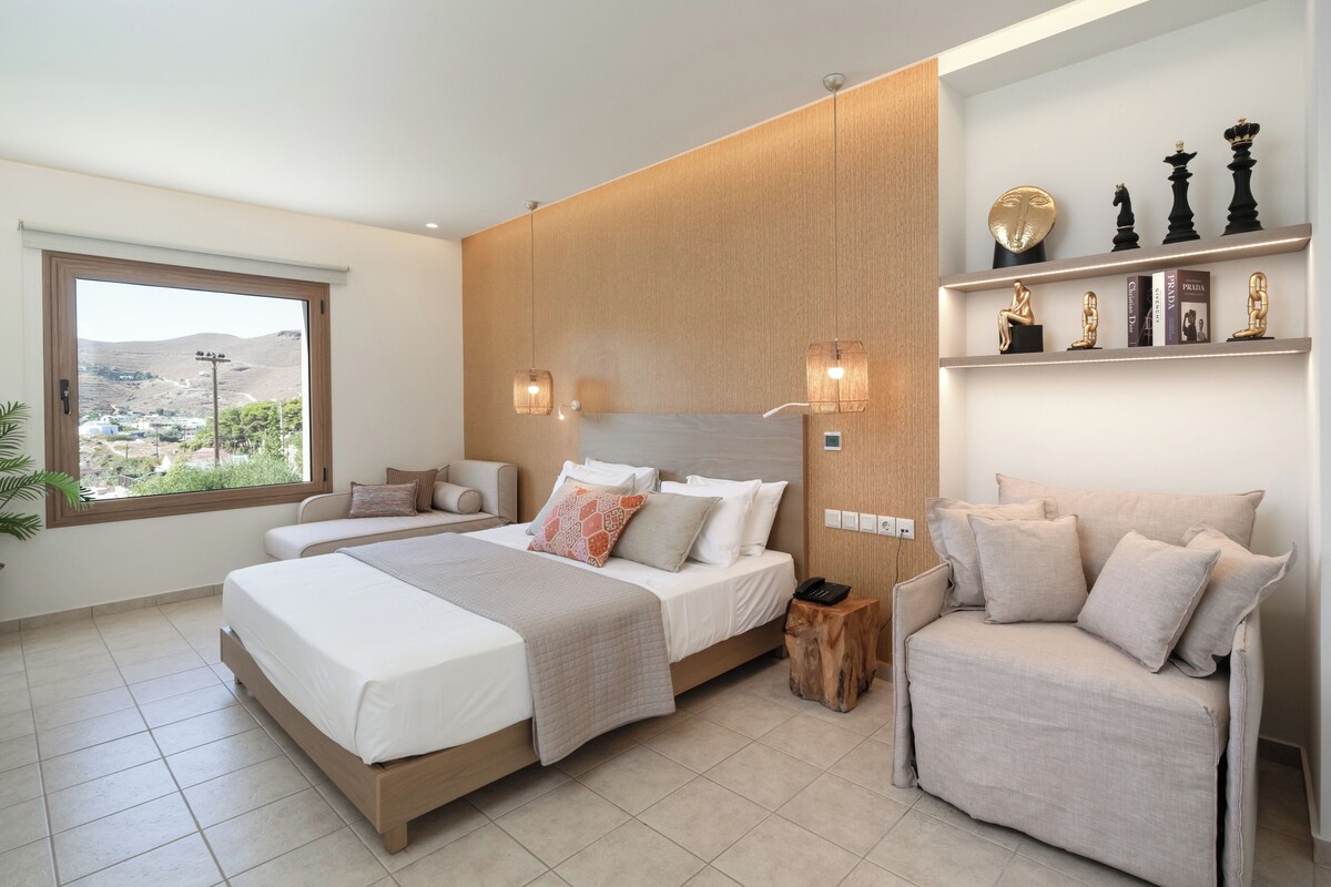 Quarto moderno com uma cama grande, um sofá e uma cadeira. Há uma janela com vista para a paisagem.