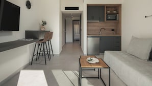 A modern kitchen with a built-in microwave and oven, a dining area with a table and chairs, and a living area with a sofa and a coffee table.