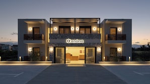A modern building with a stone facade, a sign reading "enária," and a welcoming entrance with glass doors.