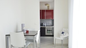 A modern kitchen with red cabinets, a white dining table, and two white chairs. - Trilo Mina 3 in Gabicce Mare (Cattolica)