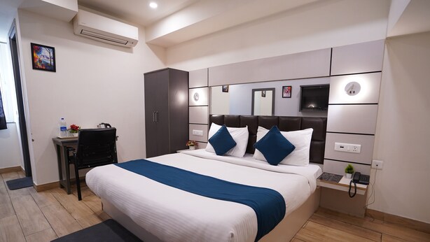 Una habitación de hotel moderna con una cama grande, un escritorio, una silla y una pequeña mesa con un teléfono y una planta.