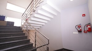 Una escalera con barandilla de metal, un extintor en la pared y una toma de corriente.