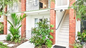 Un edificio de dos pisos con fachada de ladrillo, un balcón con barandilla de metal y una puerta con el número 2.