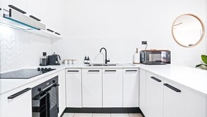 Una cocina moderna con armarios blancos, encimera negra, horno empotrado, microondas y un lavabo con grifo.