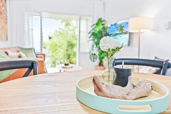 A dining table with a vase of flowers, a candle, and a piece of driftwood.