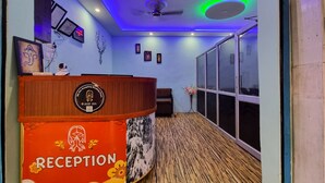 Una zona de recepción con mostrador de madera, obras de arte enmarcadas y una pantalla digital.
