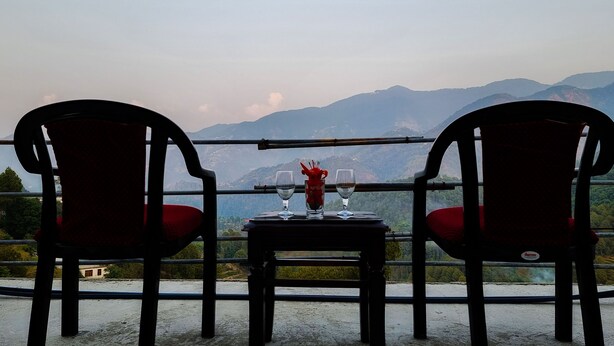 Una mesa con dos sillas frente a una vista panorámica de la montaña.