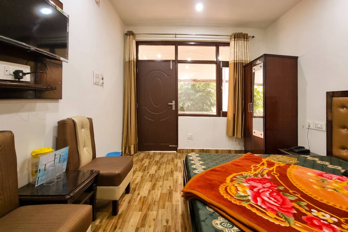 A hotel room with a bed, a desk, a chair, a television, and a wardrobe.