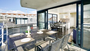 A dining area with a table set for four, overlooking a marina with boats.