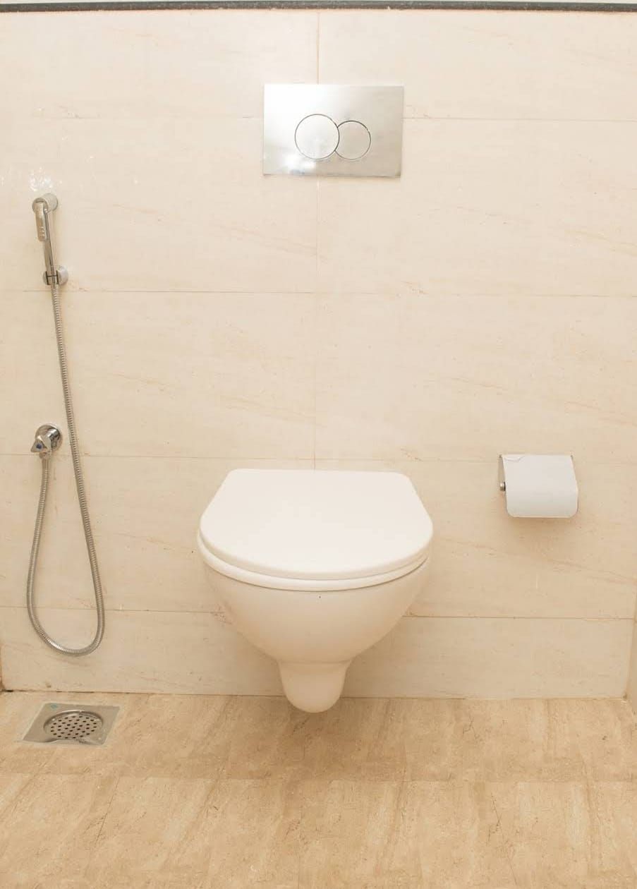Et badeværelse med toilet, bruser og toiletpapirholder.