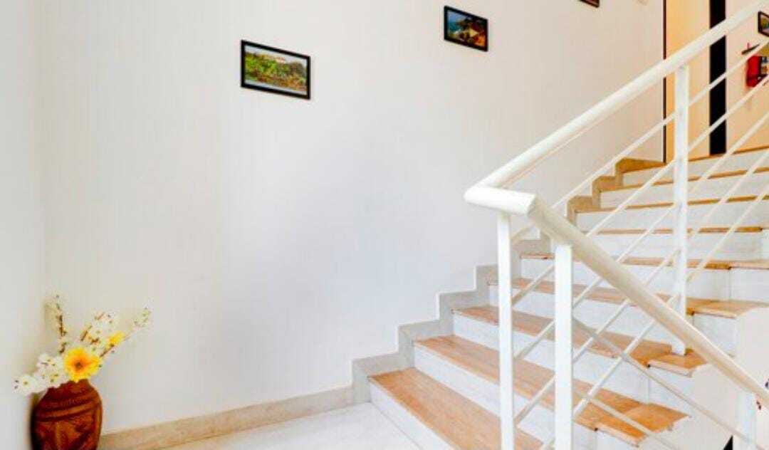 A staircase with white railings and wooden steps, leading to an upper floor.