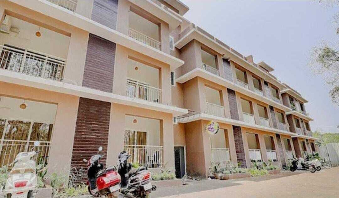 A multi-story building with balconies, a sign indicating a hotel, and parked scooters.