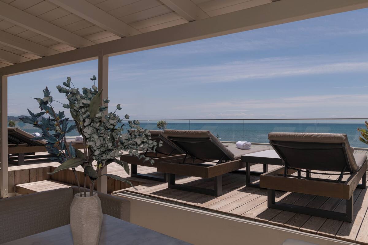 A covered outdoor seating area with lounge chairs and a large vase of flowers.