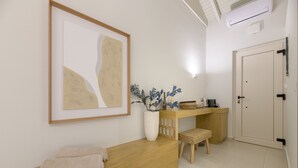Een schone, moderne badkamer met een houten bankje, een lijst met abstracte kunst, een vaas met planten en een deur met een handgreep.