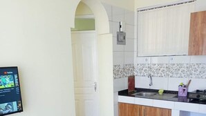 A modern kitchen with wooden cabinets, a black countertop, and a tiled backsplash. - Lux Suites Juniours Apartment Bamburi (Mombasa)