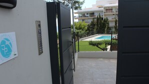 A gated entrance to a building with a pool visible in the background. - Idillic penthouse between sea and pine trees (Salou)