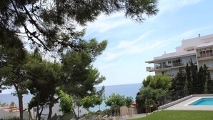 A residential area with a swimming pool, a view of the sea, and a building with balconies. - Idillic penthouse between sea and pine trees (Salou)