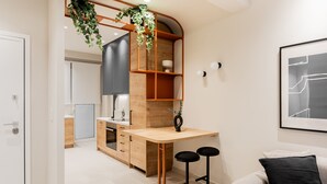 Une cuisine moderne avec des meubles en bois, un four encastré et une plante suspendue.
