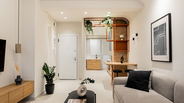 Un salon moderne avec un canapé, une table basse et un coin repas, la cuisine étant visible au fond.