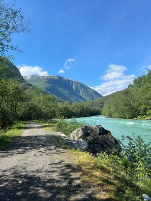 A dirt path leading to a river with a mountain in the background. - Utladalen Camping (Ardal)