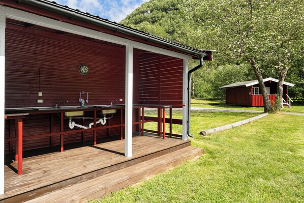 A red barn with a covered outdoor area, a wooden deck, and a small red building in the background.