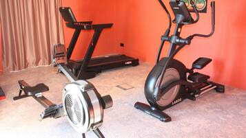 A home gym with two stationary bikes and a fan.