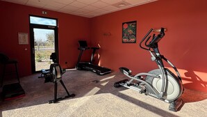 A gym with treadmills, an elliptical, and a stationary bike. There is a window with a view of the outdoors. - Aparthotel Adagio Access Porte De Camargue (Saint-Martin-de-Crau)