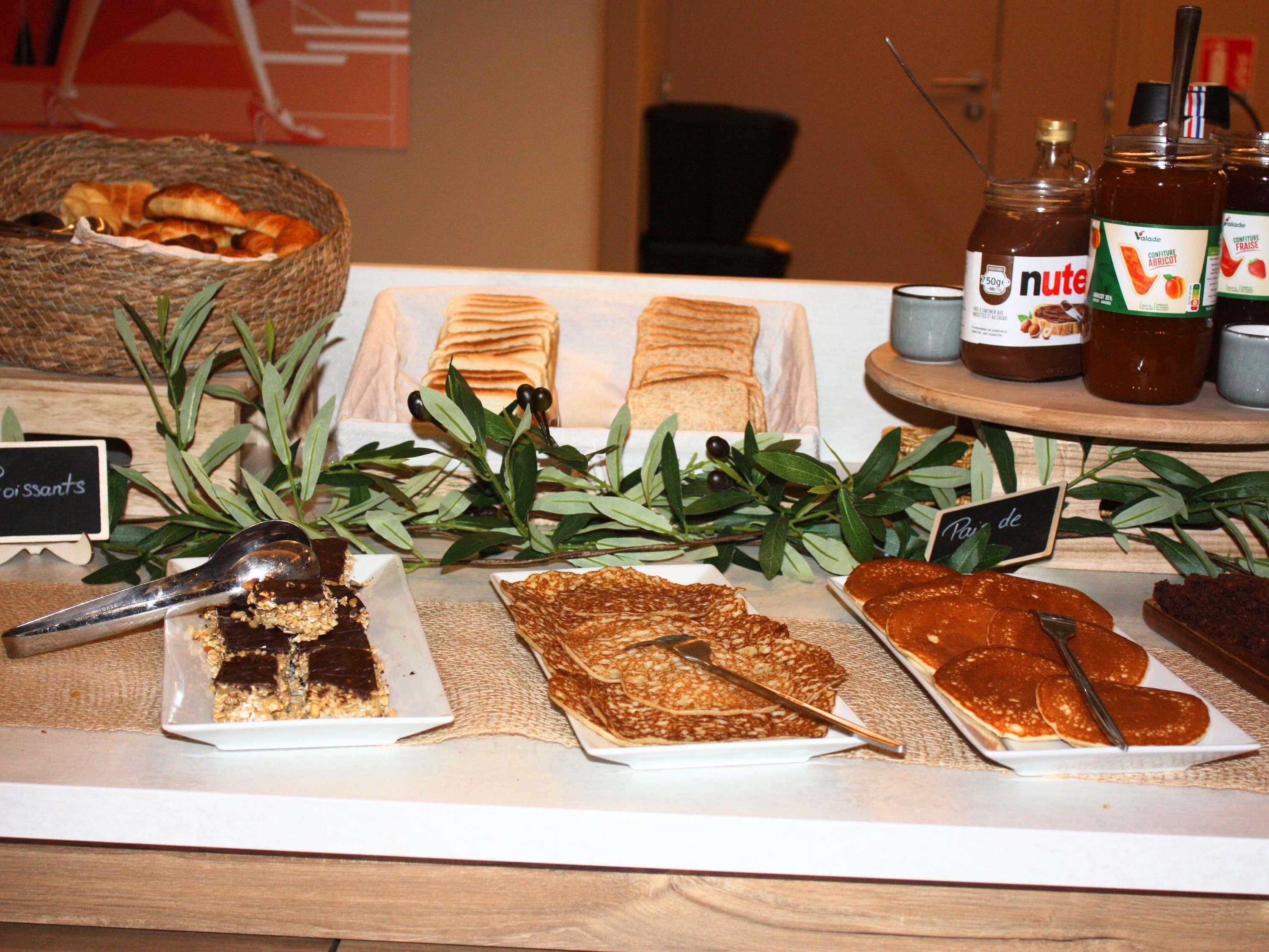A buffet table with various food items, including pastries, a chocolate dessert, and sauces.