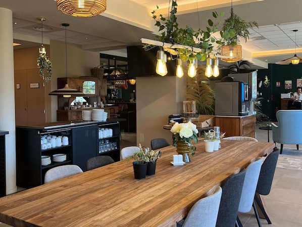 Eine moderne Küche mit Holztisch, Bar und hängenden Pflanzen.