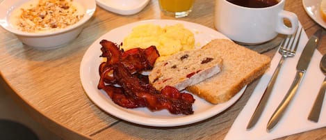 A breakfast setting with plates of eggs, bacon, toast, and pastries.