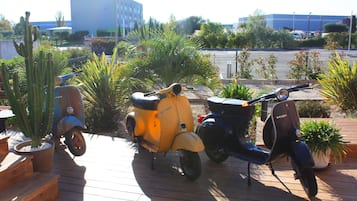 A wooden deck with three vintage scooters parked.
