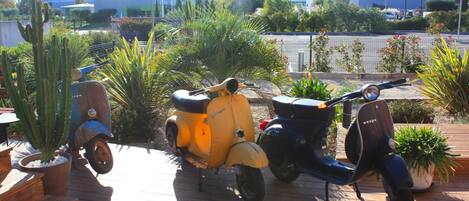 A wooden deck with three vintage scooters parked.